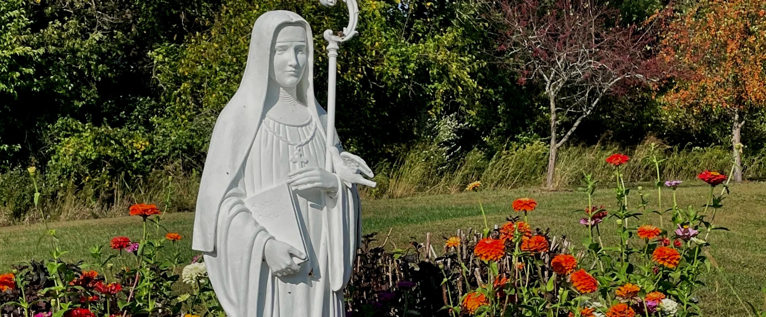 Statue of Saint Scholastica among flowers on the St. Mary Monastery grounds